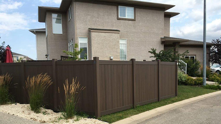 Dark brown solid privacy vinyl fencing in front of a house, an example of our Fillmore PVC fence panels.