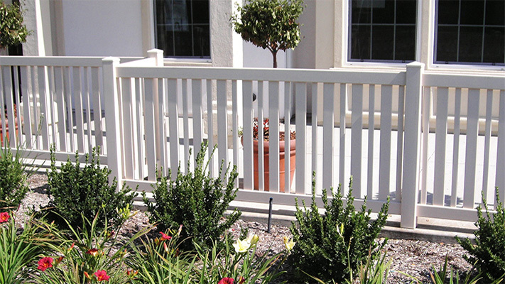 White closed picket vinyl fencing next to shrubs, some of our best HOA fencing for Westlake Village homes.