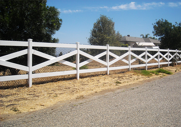 White cross buck Biola vinyl ranch rail fencing next to a road.